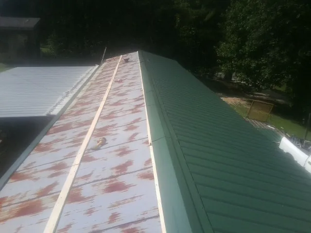 Old rusted panels beside newly installed green metal roofing — Wind Damage Roof Repair by Roofing Brothers in Watauga
