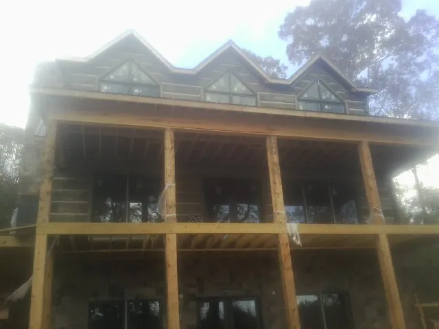 Dormers and porch framing on a large log home under construction — Roof Coating work by our crew in Watauga