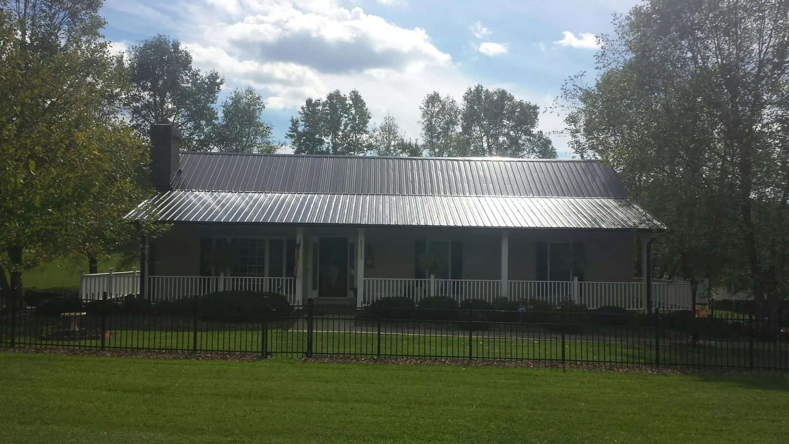 Gray metal roof on a brick ranch with a full width front porch — Gutter Guard Installation work by our crew in Watauga