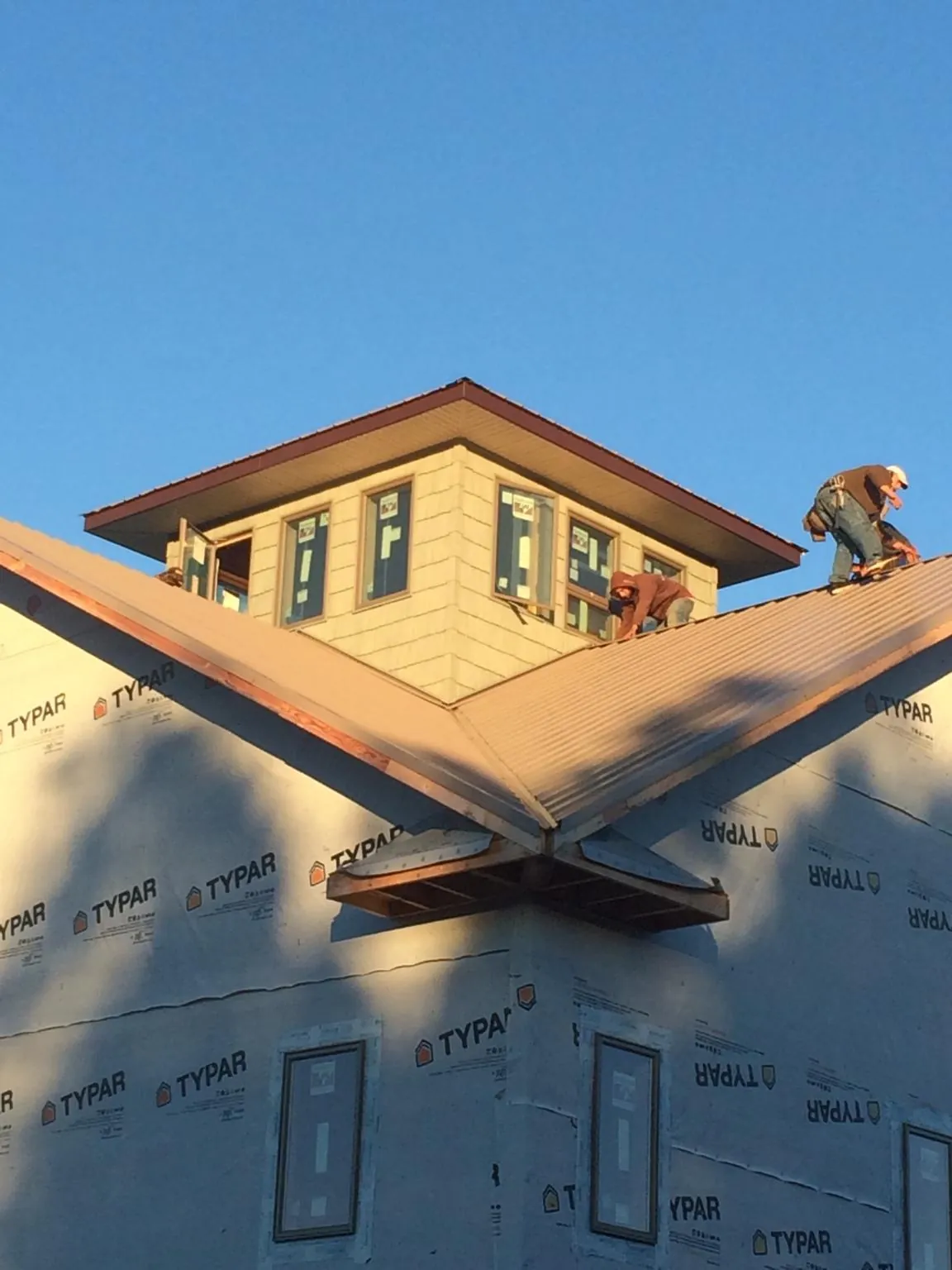 Roofers working around a rooftop cupola on a new metal roof at sunset — Roof Waterproofing in Watauga by Roofing Brothers